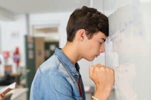 stressed high school student having difficulty solving the equation at white board