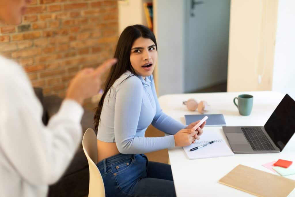 troubled teen girl using cellphone while her mom arguing and forbidding something having quarrel